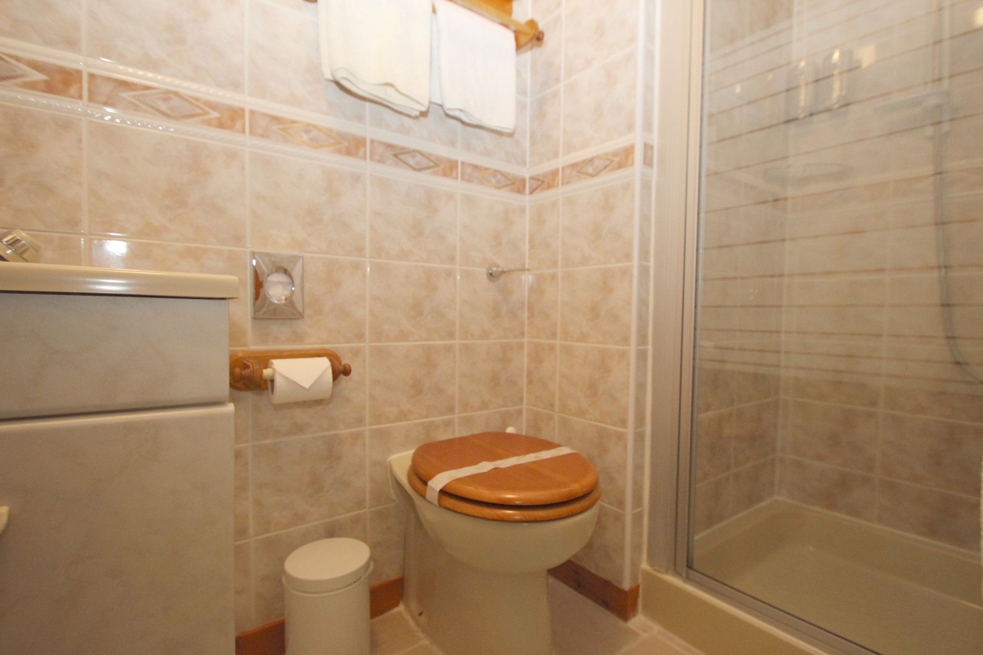 A bathroom with a toilet, a shower, and a towel rack.