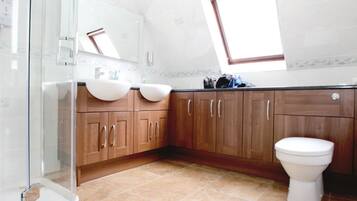 A bathroom with two sinks, a toilet, and a shower.