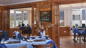 A dining area with wooden walls, large windows, and a table set for a meal. - Lochview Guest House (Ullapool)