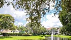 A serene park with a pond, lush greenery, and buildings in the background. - Location! Location! Location!  Sarasota!!! (Sarasota)