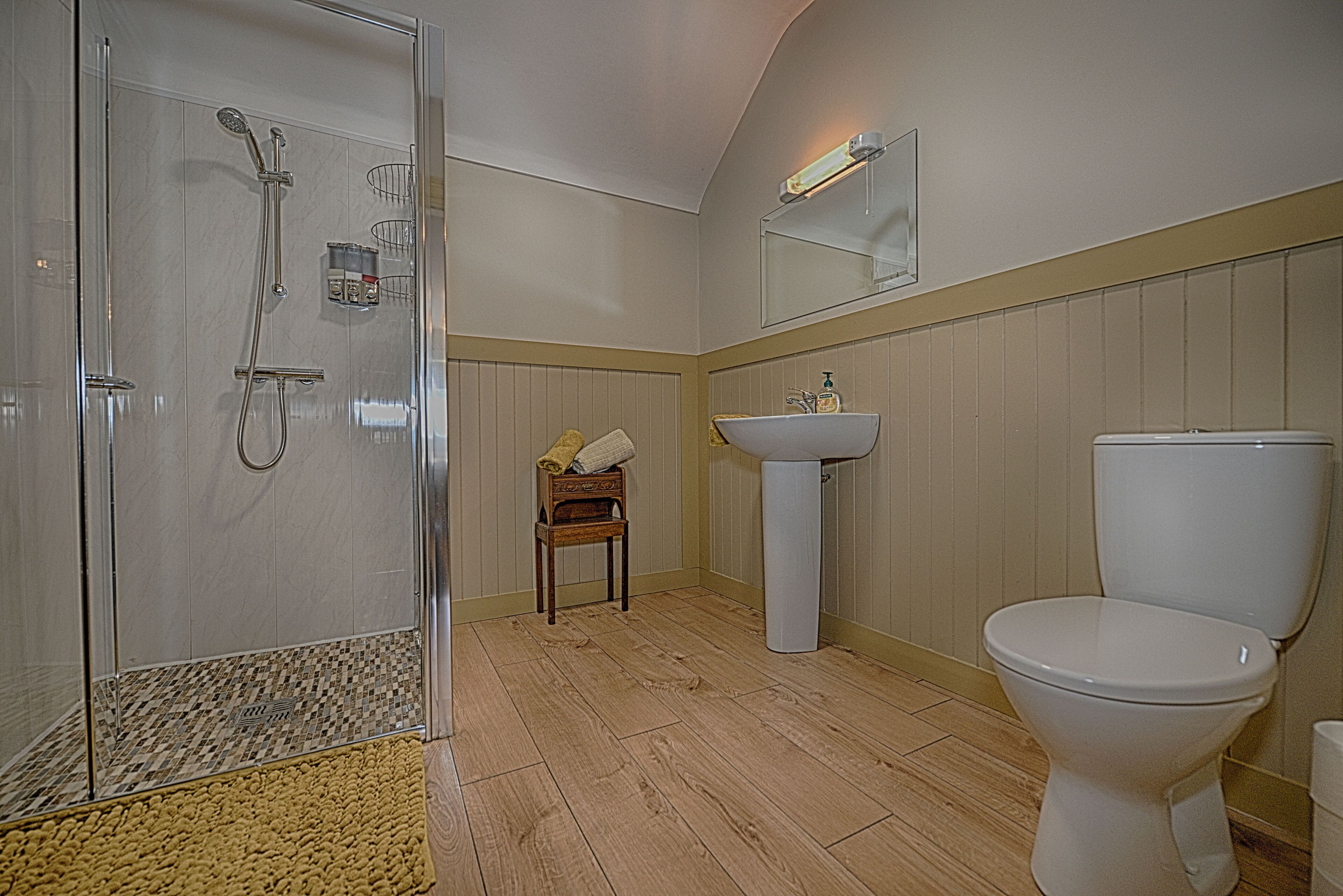 A bathroom with a glass shower enclosure, a pedestal sink, and a toilet.