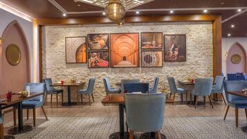 A restaurant with a stone wall, framed artwork, and blue chairs.