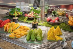 Un bufé con diversas frutas y verduras, incluyendo sandía, mangos y papaya verde.