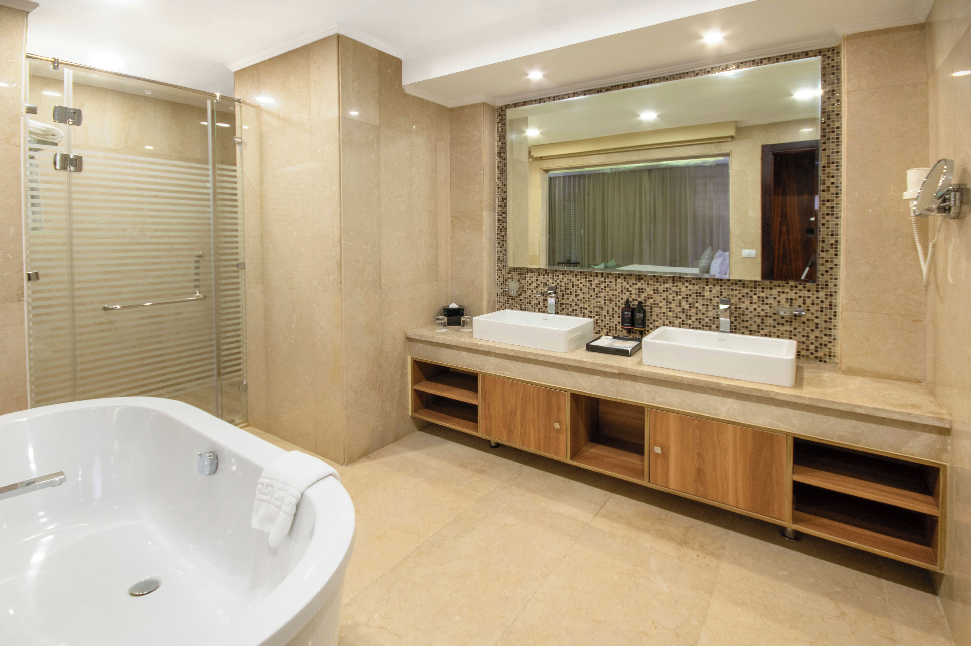 A modern bathroom with a glass-enclosed shower, a large bathtub, and a double sink vanity.