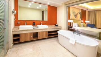 A modern bathroom with a large bathtub, two sinks, a vanity with storage, a shower area, and a large mirror.