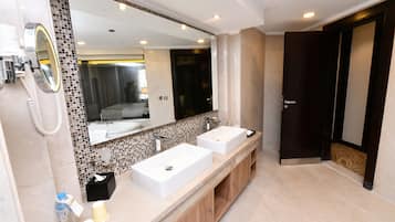 A modern bathroom with two sinks, a large mirror, and a vanity with a tiled backsplash.