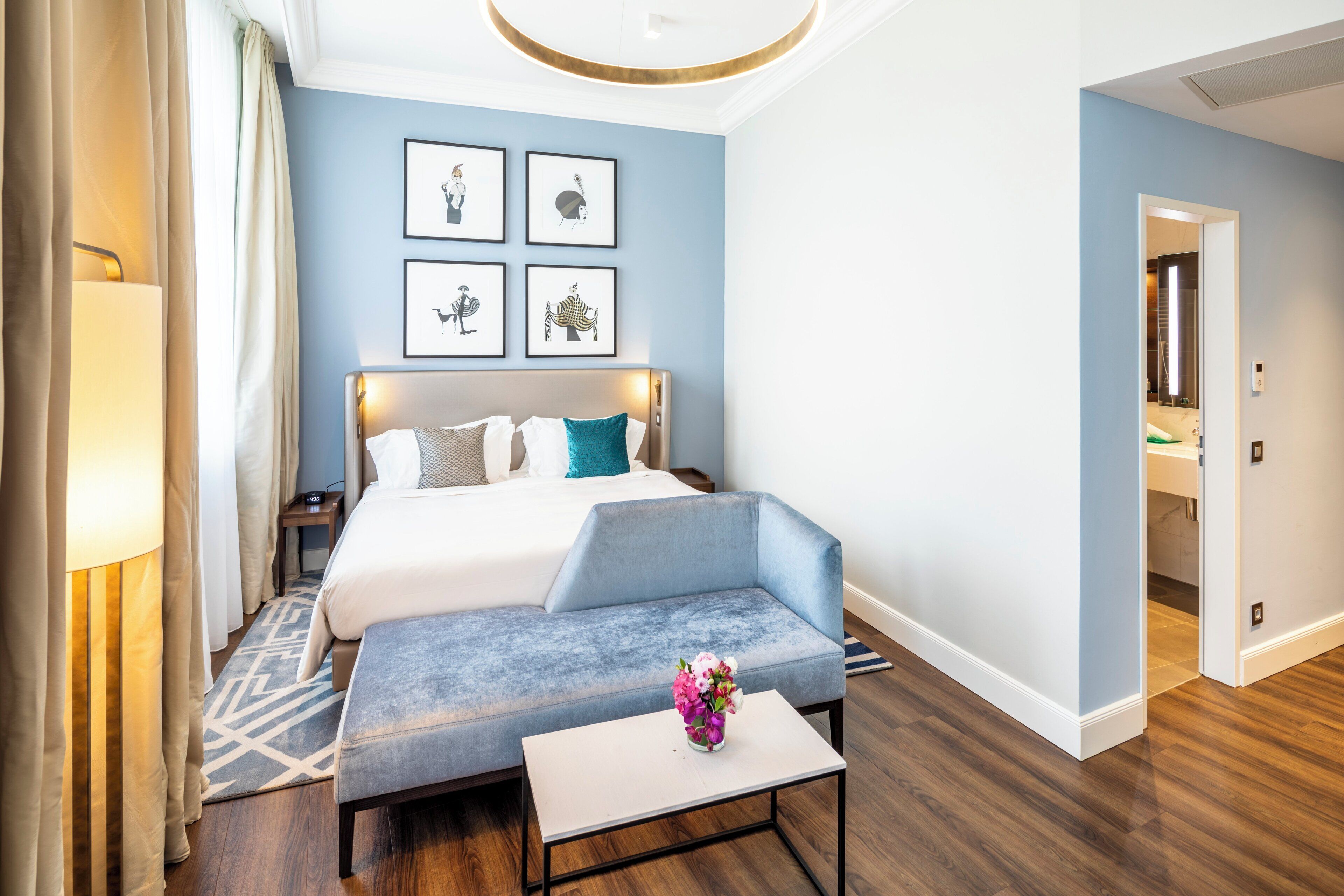 Ein modernes Hotelzimmer mit einem großen Bett, einer Sitzecke und Kunstwerken an den Wänden.