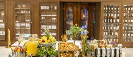 A buffet setup with various food items, drinks, and a wine display in a hotel setting.
