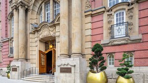 A grand entrance with a wooden door, large columns, and a sign reading "FRASER'S SUITES." - Fraser Suites Hamburg (Hamburg)