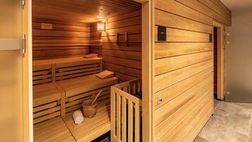 Eine Holzsauna mit Bänken und einer Sitzbank, eine Holzwand mit Bedienfeld zur Temperaturregelung sowie eine Holztür.