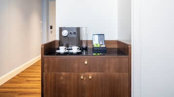 Estação de café com cafeteira, xícaras e dispensador de cápsulas em um quarto de hotel.