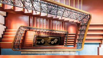 Een trap met sierlijke zwarte metalen leuningen en een houten handrail.
