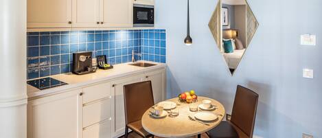 Una cocina moderna con gabinetes blancos, salpicadero de azulejos azules y un comedor con una mesa redonda y dos sillas.