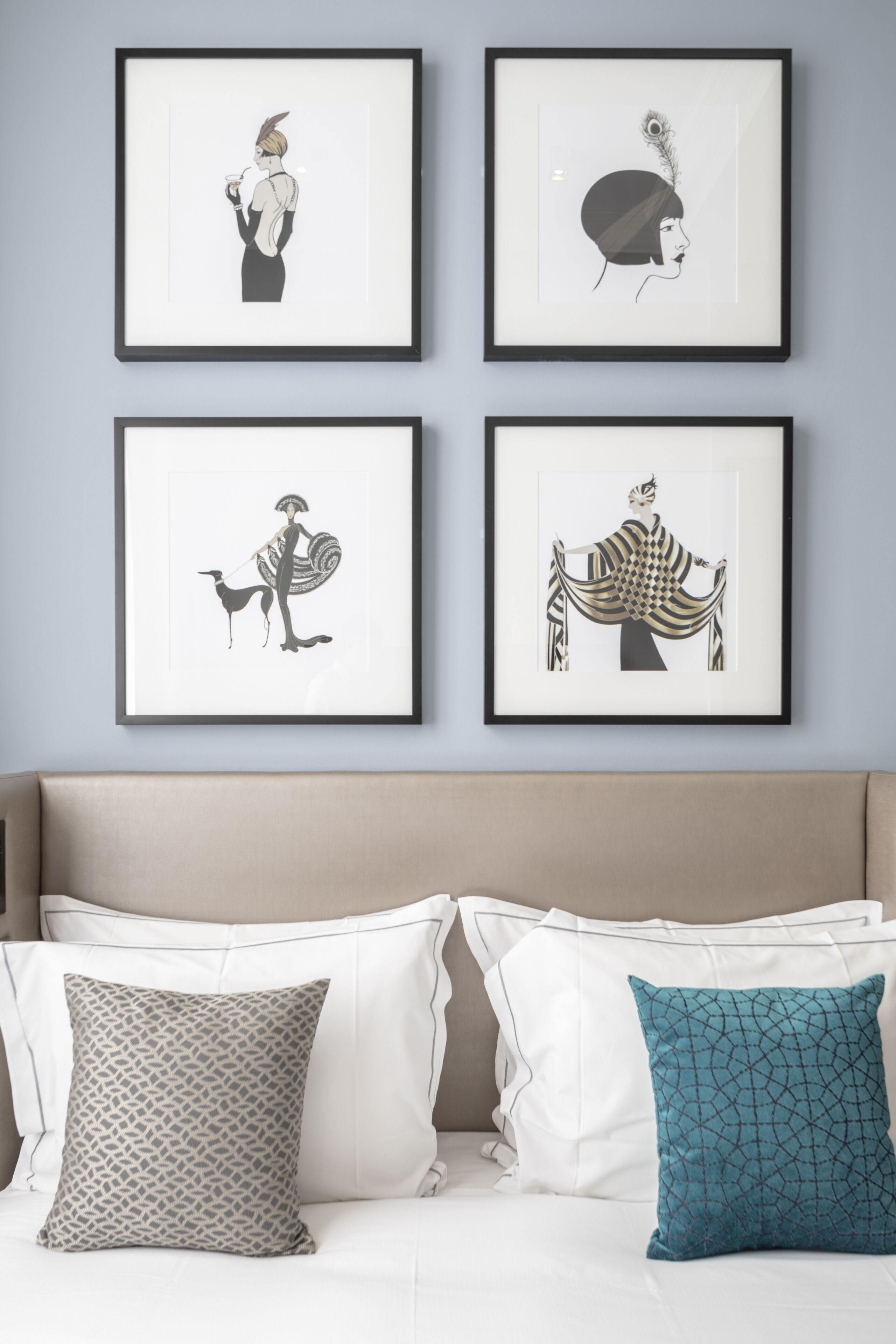 Une chambre à coucher avec un lit, deux oreillers et quatre œuvres d’art encadrées accrochées au mur.