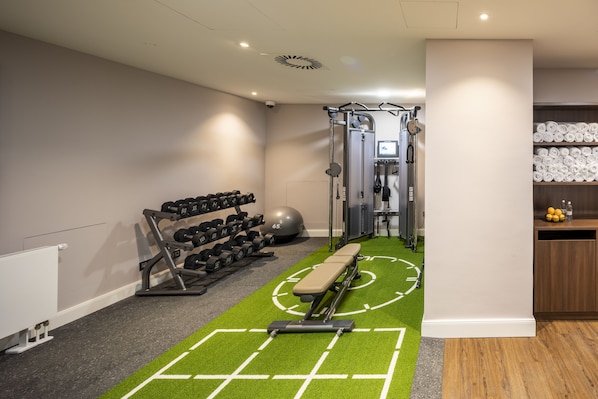 A gym with exercise equipment, a bench, and a wall-mounted TV. - Fraser Suites Hamburg (Hamburg)