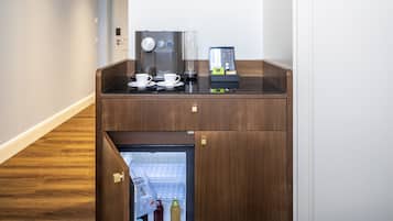 Una kitchenette compacta con cafetera, un refrigerador pequeño y una máquina de café.