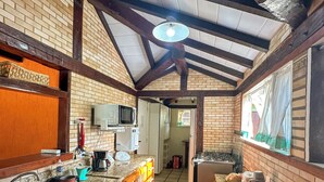 A kitchen with a tiled floor, granite countertops, wooden cabinets, and a brick wall. - Linda casa a 150 mts da Praia Ferradura (Búzios)