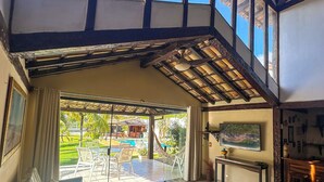 A spacious living area with a high ceiling, large windows, and a view of a pool and garden. - Linda casa a 150 mts da Praia Ferradura (Búzios)