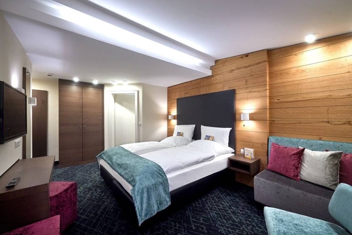Habitación de hotel con cama, escritorio, televisor y pared de madera.