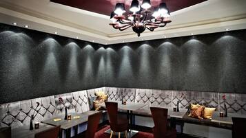 A corner seating area with a tufted headboard, a chandelier, and a dark textured wall.