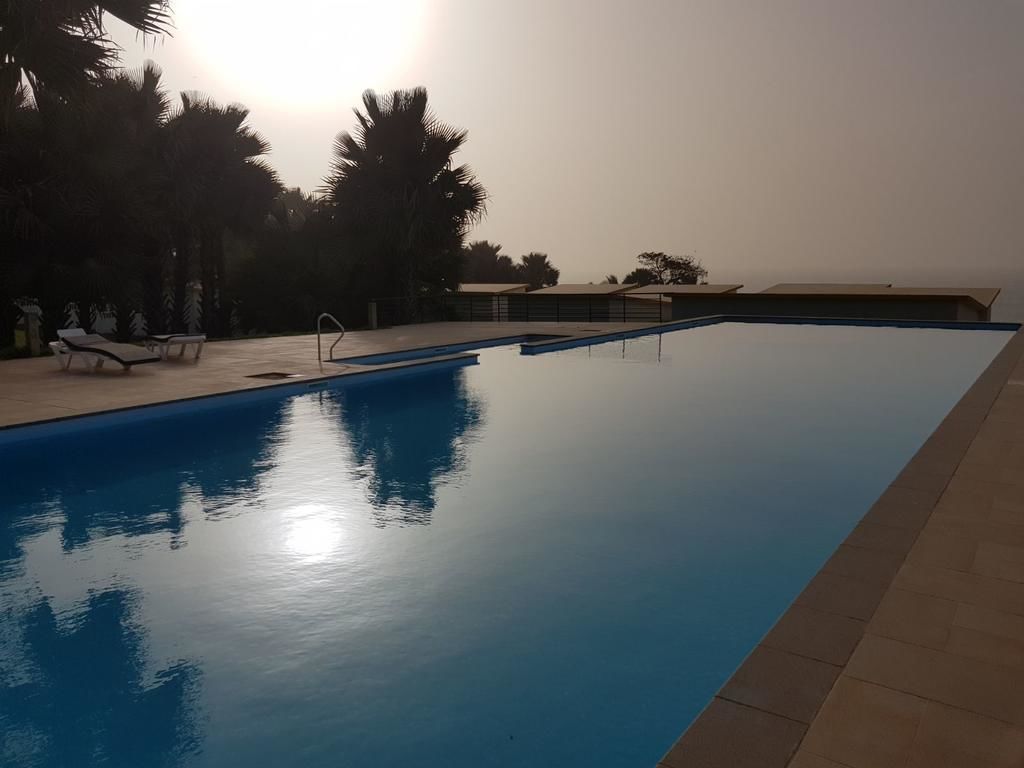 A swimming pool with lounge chairs and palm trees.