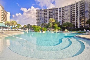 Una gran piscina con agua azul cristalina, rodeada de exuberante vegetación y palmeras.