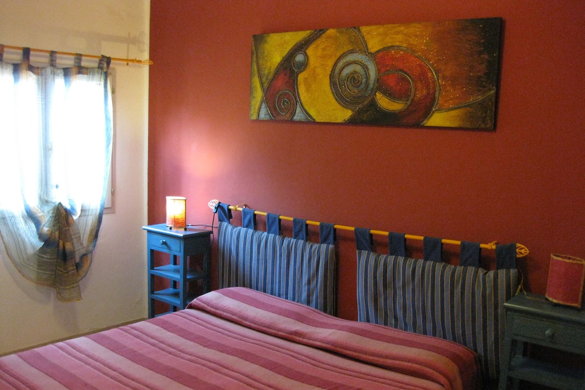 Ein Schlafzimmer mit einem Bett, einem Nachttisch, einer Lampe und einem Bild an der Wand.