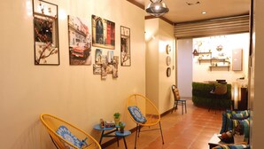 A hotel lobby with wicker chairs, a reception desk, and wall art.