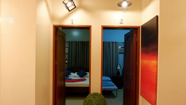 A hallway with two doors, each leading to a bedroom with a bed, nightstand, and curtains.