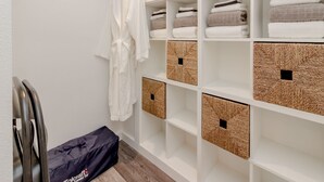 A hotel closet with neatly folded towels, a robe hanging, and storage boxes. - Relaxing Lakefront Suite (Federal Way)