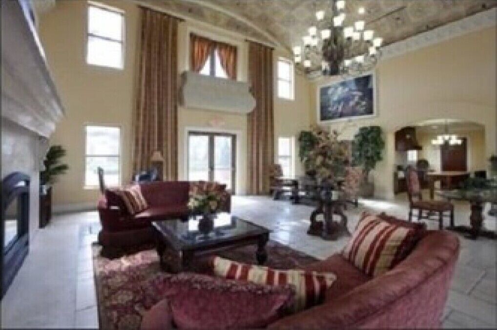 A spacious living room with a fireplace, a dining area, and a chandelier.