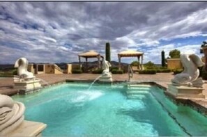 A swimming pool with a water fountain, surrounded by stone sculptures and a pergola. - Luxurious Villa at Lake Las Vegas (Henderson)