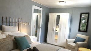 A bedroom with a bed, a wardrobe, a chair, and a bedside table. - La Casita de Abuela (Hato Rey Central)
