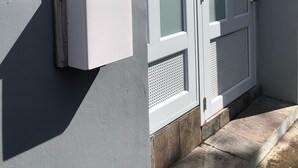 A white exterior wall with a weathered wooden plaque and a white electrical box. - La Casita de Abuela (Hato Rey Central)