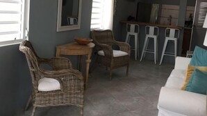 A room with a dining area, a white sofa, and wicker chairs. - La Casita de Abuela (Hato Rey Central)