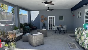A covered patio area with wicker furniture, ceiling fans, and potted plants. - La Casita de Abuela (Hato Rey Central)