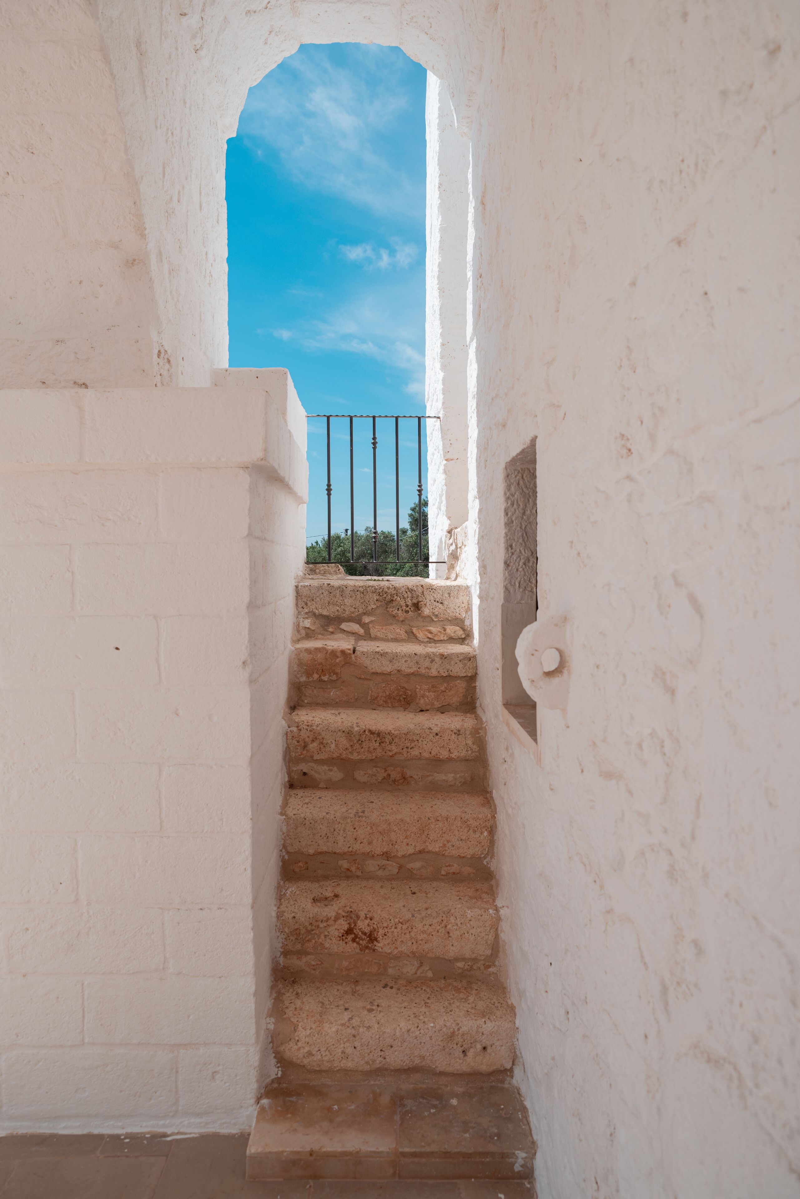 Un escalier menant à un balcon, avec un ciel bleu dégagé en arrière-plan.