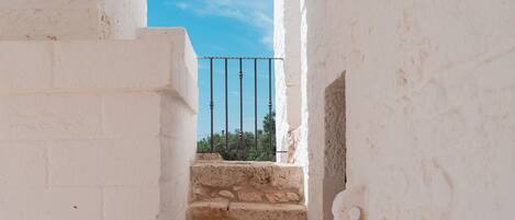 Un escalier menant à un balcon, avec un ciel bleu dégagé en arrière-plan.
