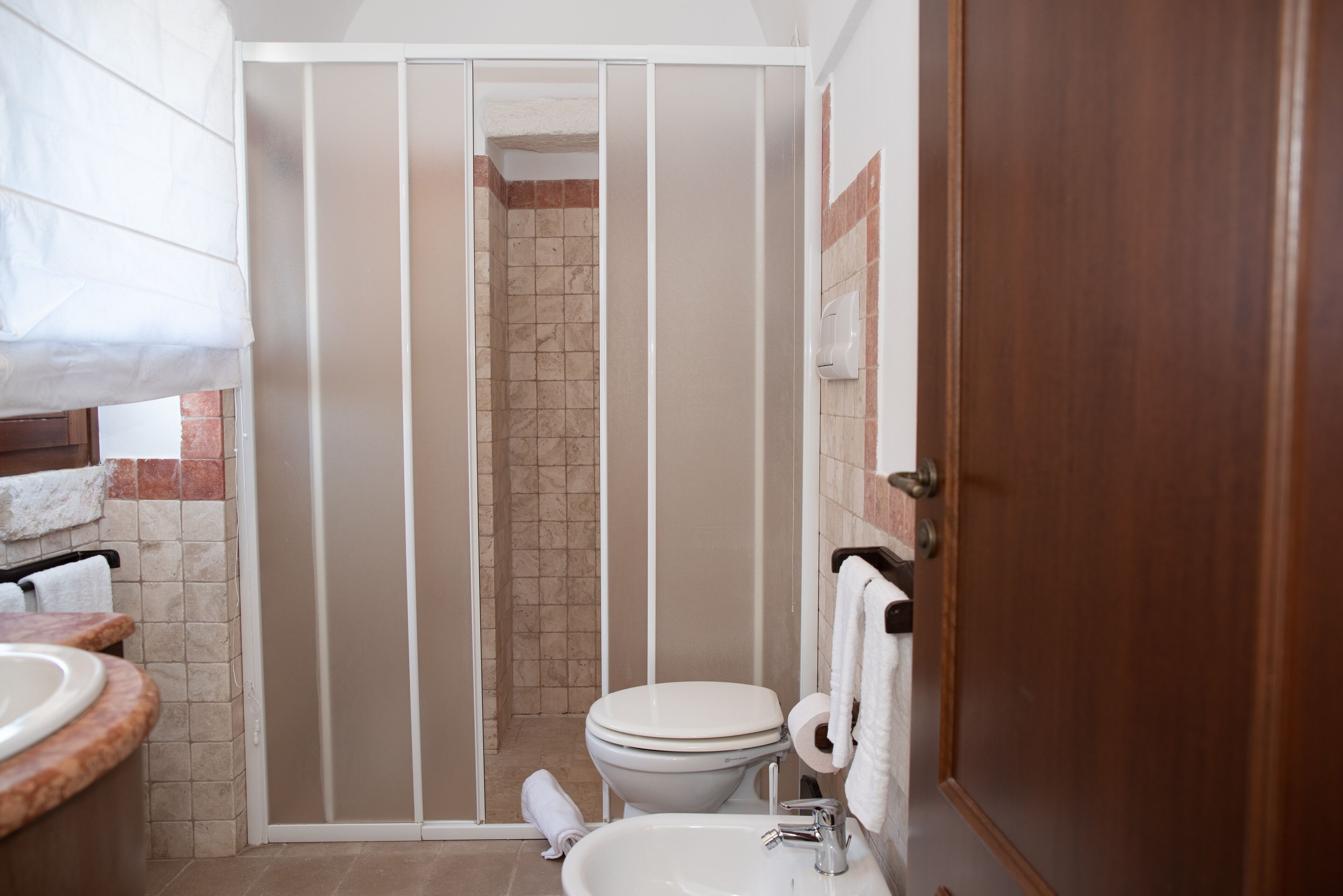 Une salle de bain comprenant un espace douche, des toilettes, un lavabo et des porte-serviettes.