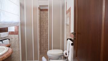 Une salle de bain comprenant un espace douche, des toilettes, un lavabo et des porte-serviettes.