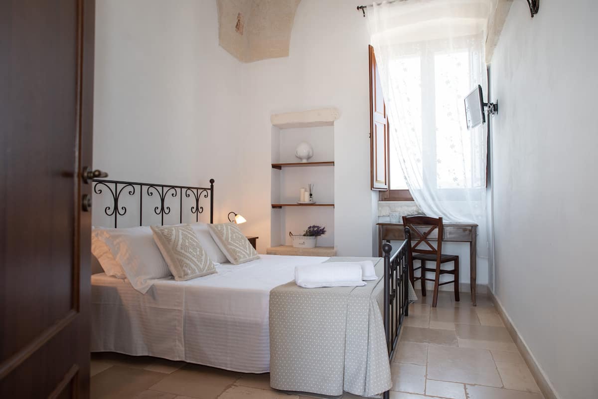 A bedroom with a bed, bedside tables, a desk, and a chair.