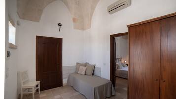 A bedroom with a bed, a wooden wardrobe, a chair, and a door.