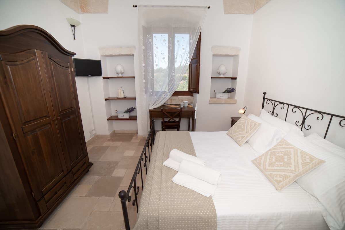 A bedroom with a bed, a desk, and a wardrobe.