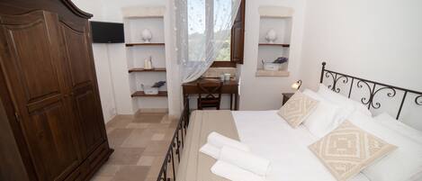 A bedroom with a bed, a desk, and a wardrobe.