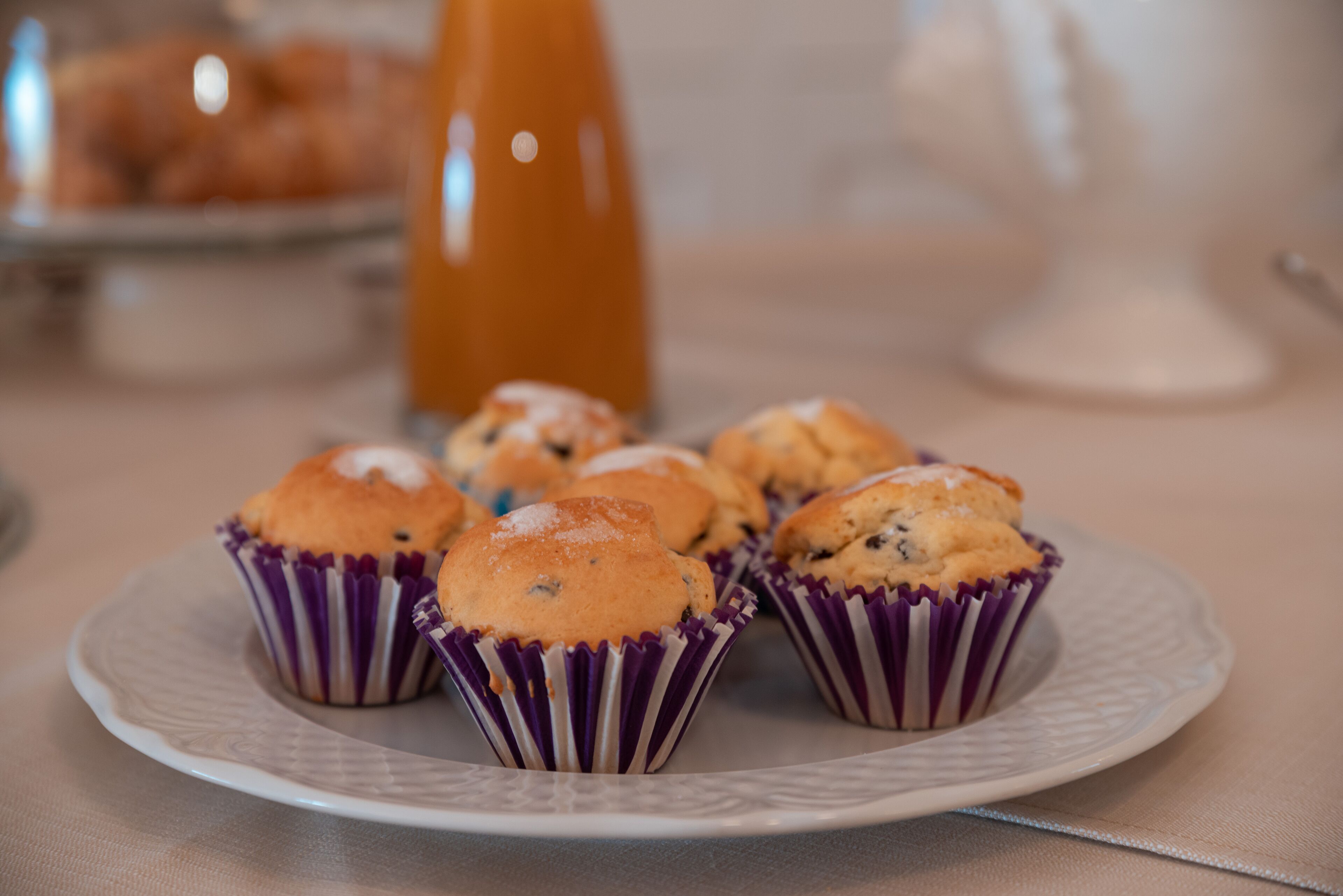 Un plato con muffins en vasos de papel morados sobre un plato blanco.