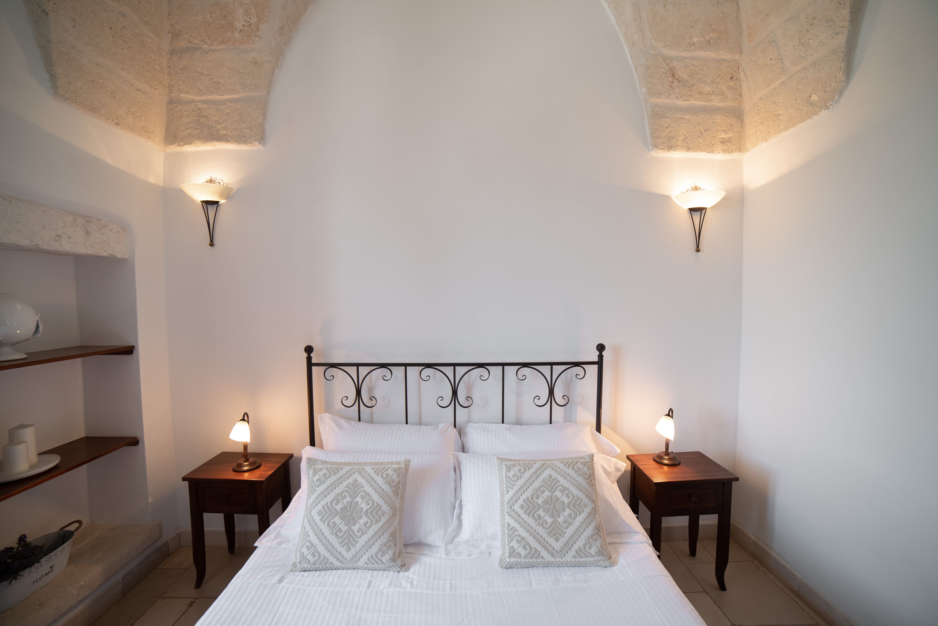 Un dormitorio con cama, dos mesitas de noche y apliques de pared.