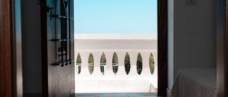 Puerta abierta que da a un balcón con vista a la playa.