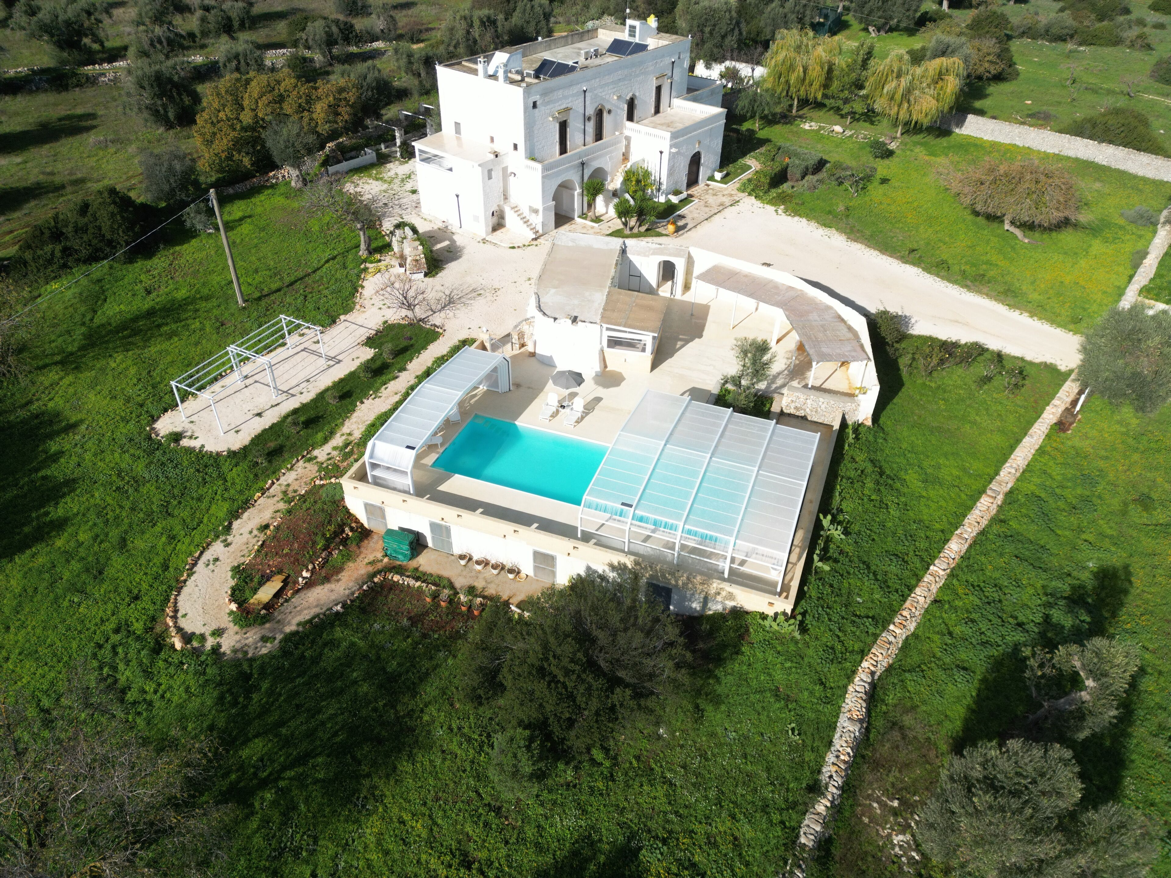 A large house with a swimming pool, surrounded by greenery.