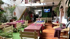 Un restaurante acogedor con mesas y sillas de madera, césped artificial verde y macetas de terracota.