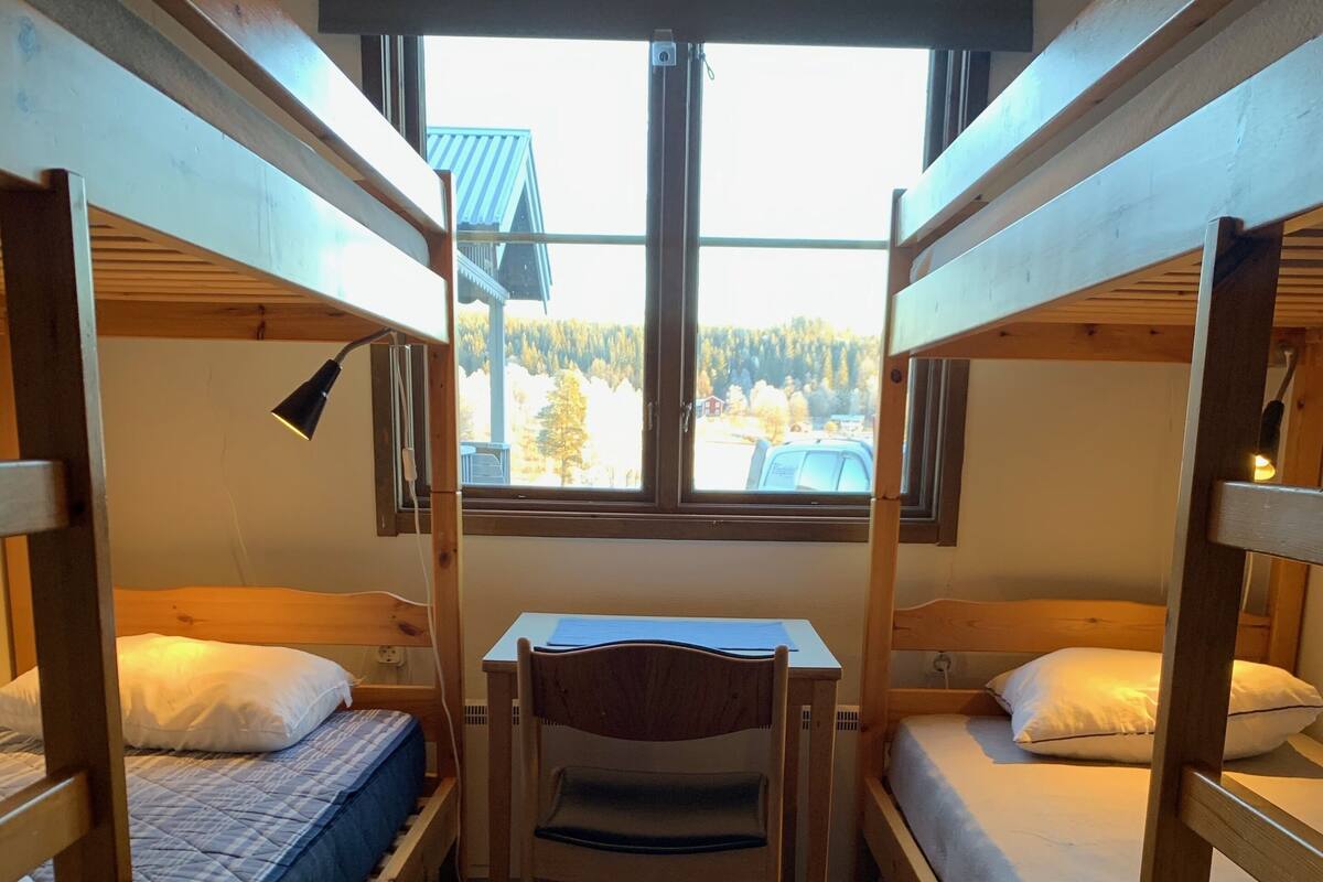 Huone, jossa on kaksi kerrossänkyä, työpöytä ja tuoli.